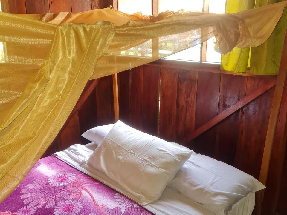 bed with a mosquito net over it in an overwater lodge