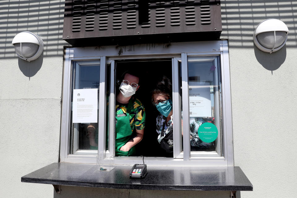 EDGEWATER, COLORADO - APRIL 07:  Starbucks employees wear a mask while working the drive-thru window on April 07, 2020 in Edgewater, Colorado. Starting today Starbucks will require all employees to wear facemasks at work. The chain has closed in-store cafes however drive-thru locations remain open. (Photo by Matthew Stockman/Getty Images)