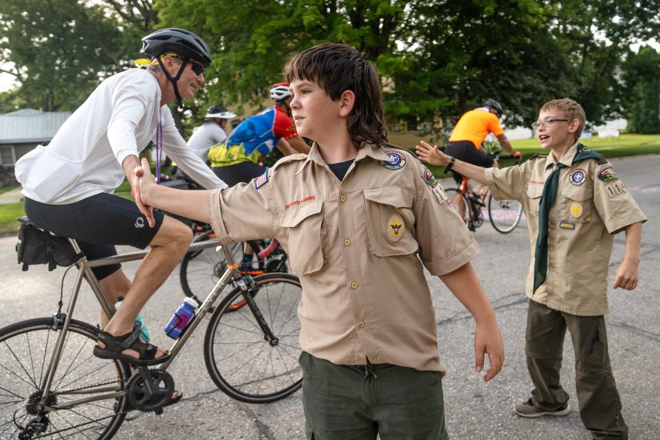 Landin Pegg of Scranton and Wyatt Field of Carroll give riders high fives while advertising breakfast burritos for sale by their Boy Scout troop during Day 3 of RAGBRAI 50 on Tuesday in Glidden.