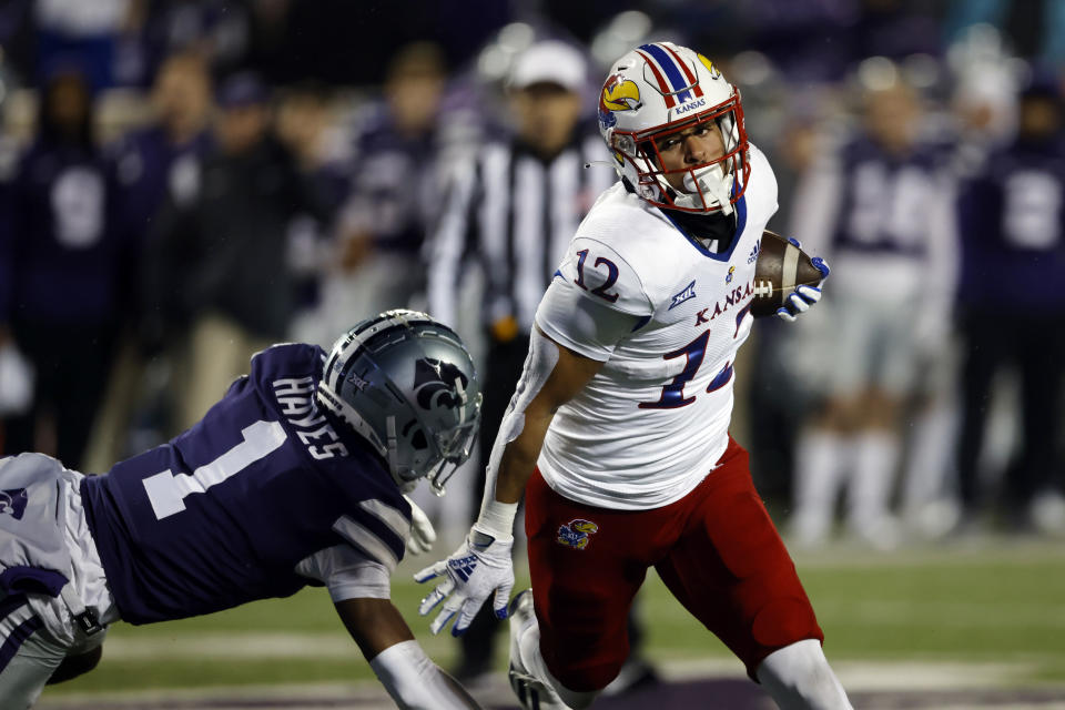 Kansas running back Torry Locklin (12) avoids Kansas State safety Josh Hayes (1) to score a touchdown during the first quarter of an NCAA college football game Saturday, Nov. 26, 2022, in Manhattan, Kan. (AP Photo/Colin E. Braley)