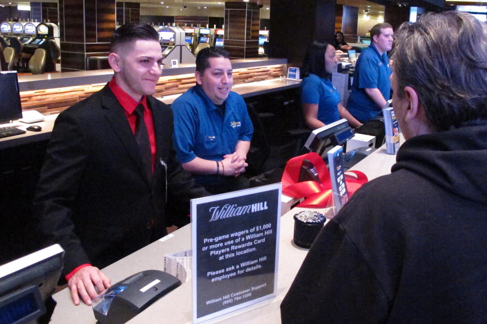 Customers make bets at the William Hill sportsbook inside the Tropicana casino in Atlantic City N.J., on March 8, 2019. Caesars Entertainment announced Wednesday, Sept. 30, 2020, it is buying William Hill for $3.7 billion. (AP Photo/Wayne Parry)