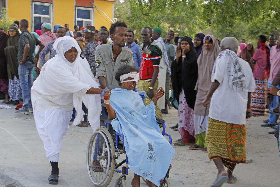 A civilian who was wounded in suicide car bomb attack is helped to be taken to hospital in Mogadishu, Somalia, Saturday, Dec, 28, 2019. A police officer says a car bomb has detonated at a security checkpoint during the morning rush hour in Somalia's capital. (AP Photo/Farah Abdi Warsame)