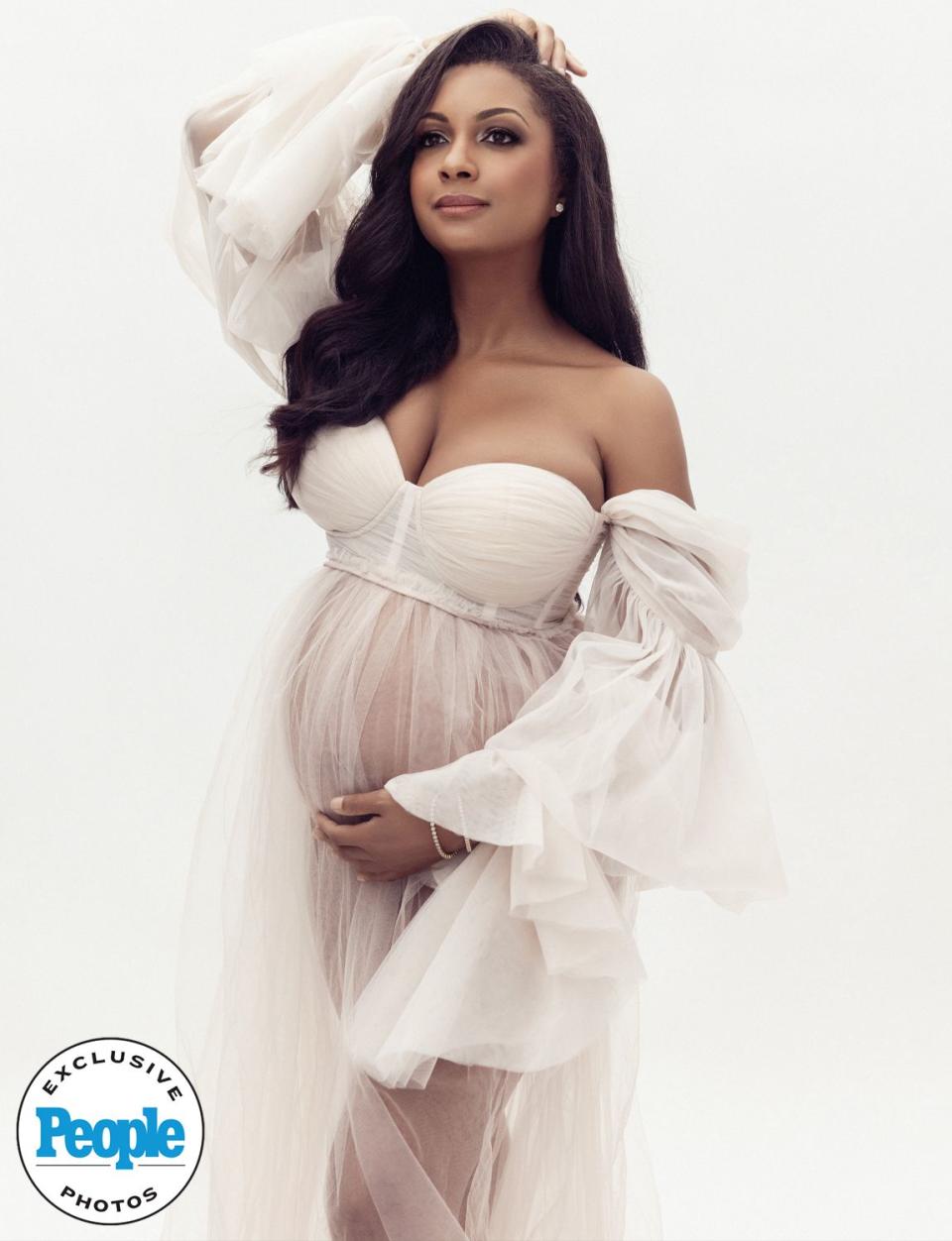 <p>Lola Melani Photography</p> Eboni K. Williams cradles her baby bump as she poses for a photoshoot to celebrate the news that she