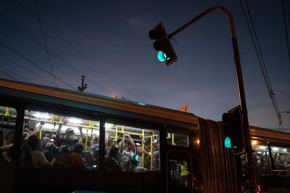 Commuters, some wearing protective face masks, ride a bus amid the COVID-19 coronavirus pandemic in Rio de Janeiro, Brazil, Thursday, June 25, 2020. Authorities say buses can operate with people standing, limited to 2 commuters per square meter, and marks on the floor will have to be painted in order to help people to keep their distance. (AP Photo/Leo Correa)