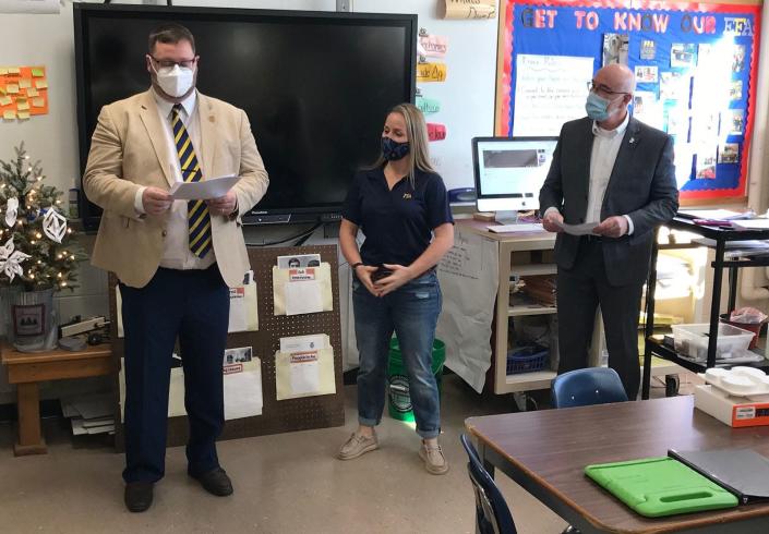 New York FFA Director Derek Hill, left, reads off some heartfelt tributes to Hamilton Central School agriculture teacher Johanna Bossard, center, Jan. 21 as district Superintendent Bill Dowsland, right, and the audience in her classroom listen.
