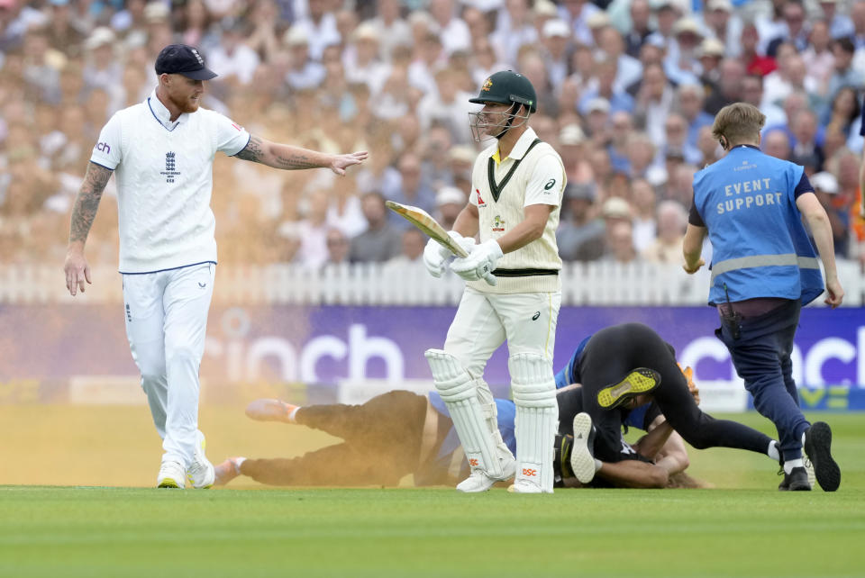 England's Ben Stokes gestures to Australia's David Warner, as a Just Stop Oil protestor is pushed to the ground during day one of the second Ashes Test cricket match at Lord's Cricket Ground, London, England, Wednesday, June 28, 2023. (AP Photo/Kirsty Wigglesworth)