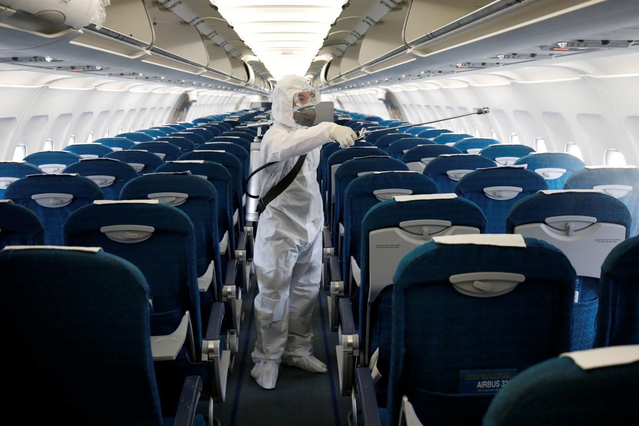 A health worker sprays disinfectant inside a Vietnam Airlines airplane to protect from the recent coronavirus outbreak, at Noi Bai airport in Hanoi, Vietnam February 21, 2020. REUTERS/Kham