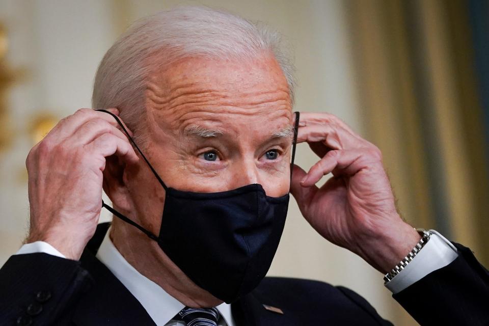 President Joe Biden puts on a face covering as he concludes his remarks in the State Dining Room of the White House on March 15, 2021.