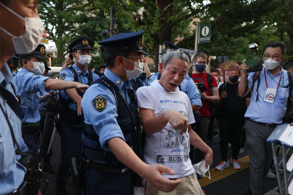 <p>Police officers escort a protester protesting against the Tokyo 2020 Olympic Games after he got into an argument with a supporter of the Olympic Games near the Olympic Stadium in Tokyo on July 23, 2021, ahead of the opening ceremony of the 2020 Tokyo Olympic Games. (Photo by Yuki IWAMURA / AFP) (Photo by YUKI IWAMURA/AFP via Getty Images)</p> 