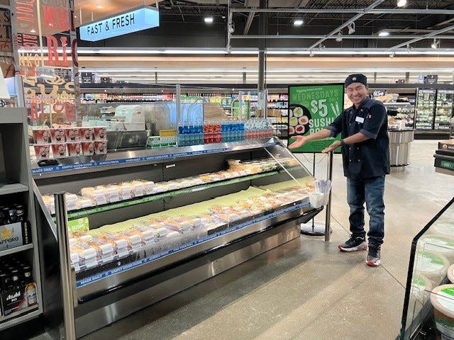 Lin Aung shows off some of his creations at the newly remodeled South Lyon market.