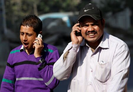 Men talk on their mobile phones while walking on a road in Kolkata, India January 6, 2017. REUTERS/Rupak De Chowdhuri