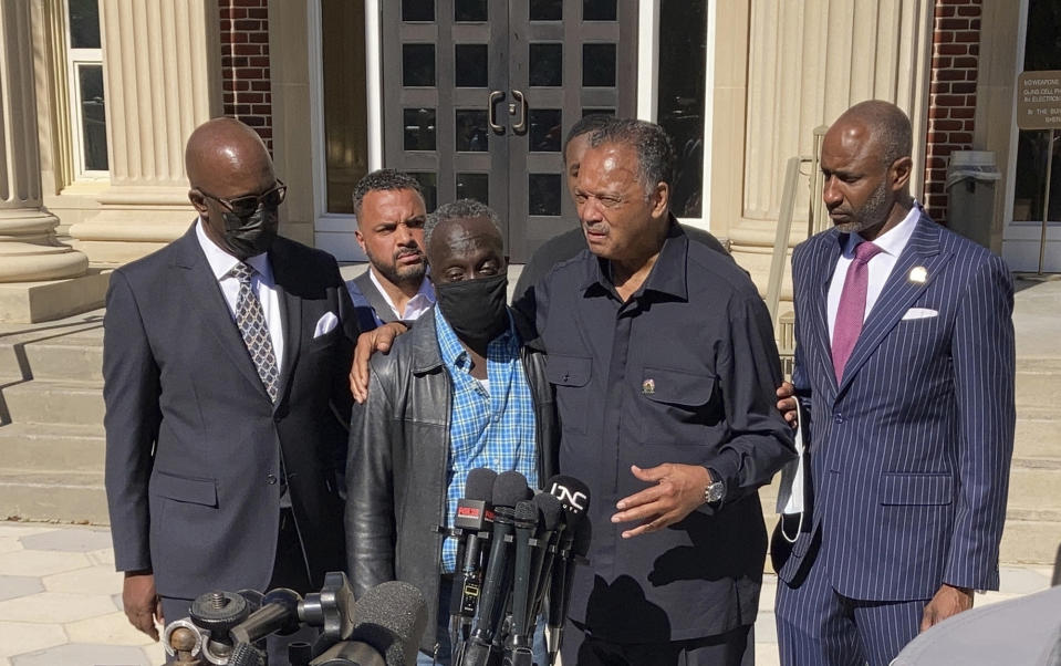 The Rev. Jesse Jackson, center right, puts his arm around Ahmaud Arbery's father, Marcus, in a news conference during a break of the trial of three men charged with killing Arbery taking place at the Glynn County courthouse in Brunswick, Georgia, on Tuesday, Nov. 16, 2021. A judge denied a defense attorney's request to kick Jackson out of the courtroom. (AP Photo/Jeffrey Collins)