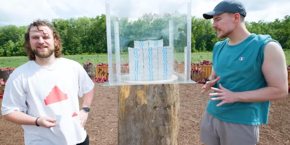 Will and MrBeast standing in front of the glass case of cash.