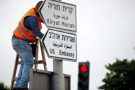 A worker hangs a road sign directing to the U.S. embassy, in the area of the U.S. consulate in Jerusalem, May 7, 2018. REUTERS/Ronen Zvulun