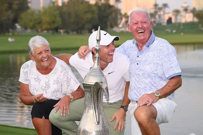 Photo showing Rory McIlroy laughing with his parents, Rosie and Gerry, as they pose with the Dubai Desert Classic trophy