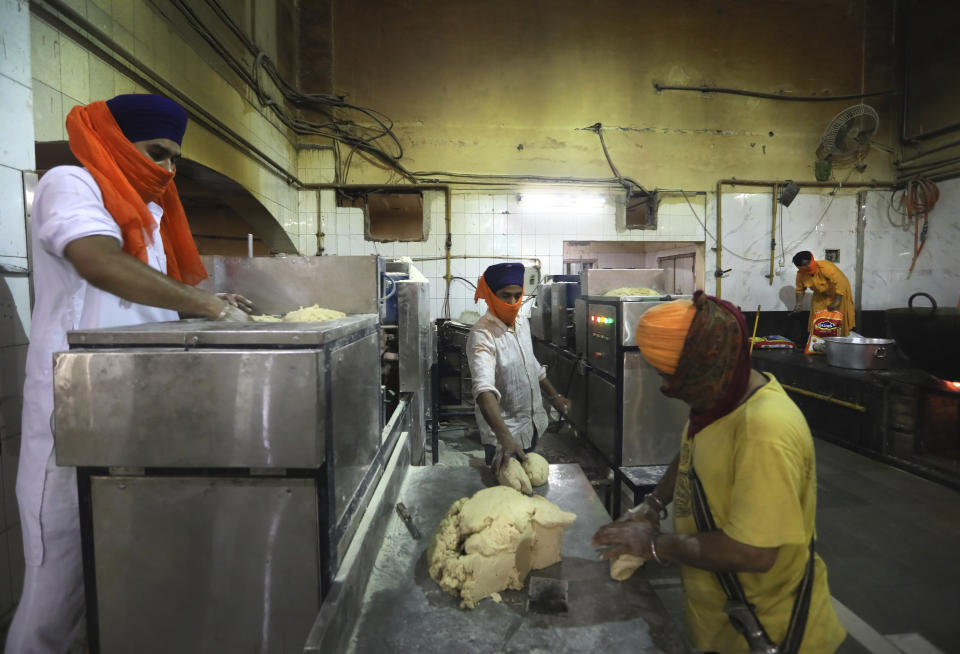 Sikh volunteers put dough into a machine that makes chapati, thin unleavened bread, in the kitchen hall of the Bangla Sahib Gurdwara in New Delhi, India, Sunday, May 10, 2020. The Bangla Sahib Gurdwara has remained open through wars and plagues, serving thousands of people simple vegetarian food. During India's ongoing coronavirus lockdown about four dozen men have kept the temple's kitchen open, cooking up to 100,000 meals a day that the New Delhi government distributes at shelters and drop-off points throughout the city. (AP Photo/Manish Swarup)