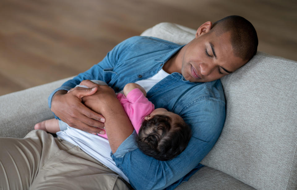 A man sleeping with his baby on the sofa