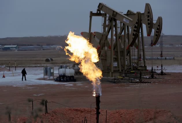 In this Oct. 22, 2015, file photo, workers tend to oil pump jacks behind a natural gas flare near Watford City, North Dakota.  (Photo: via Associated Press)