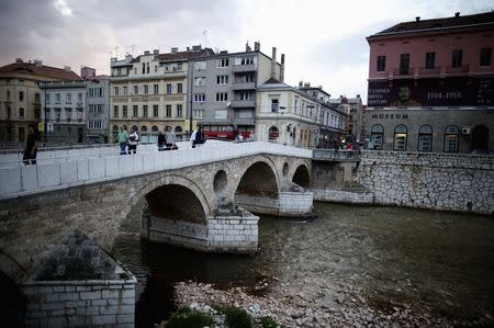 People cross the Latin Bridge and street corner in front of the historical landmark, where Archduke Franz Ferdinand and his wife Sophie were assassinated, in Sarajevo June 24, 2014. REUTERS/Dado Ruvic