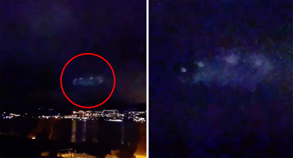 UFO in night sky over lake and town