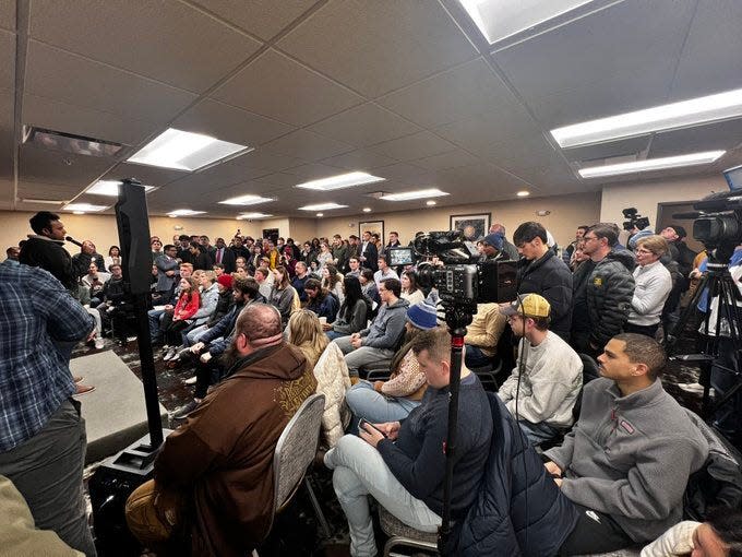 John Southerland of Spokane, Washington, front left in the brown coat, watches Vivek Ramaswamy speak at the Comfort Inn & Suites at 1625 Jordan Creek Parkway in West Des Moines on Friday, Jan. 12, 2024. Ramaswamy spoke to a crowd of more than 100 people.