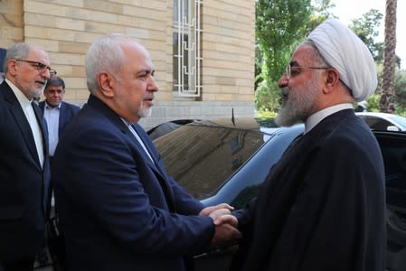 Iranian President Hassan Rouhani shakes hands with Iran's Foreign Minister Mohammad Javad Zarif in Tehran