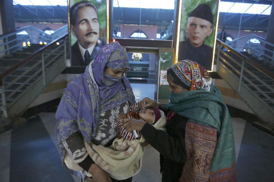 A health worker administers a polio vaccine to a child at a railway station in Lahore, Pakistan, Monday, Jan. 24, 2022. Pakistani authorities on Monday launched this year's first nationwide anti-polio campaign despite facing a sudden surge of coronavirus cases in an effort aimed eradicating the crippling children's disease. (AP Photo/K.M. Chaudhry)