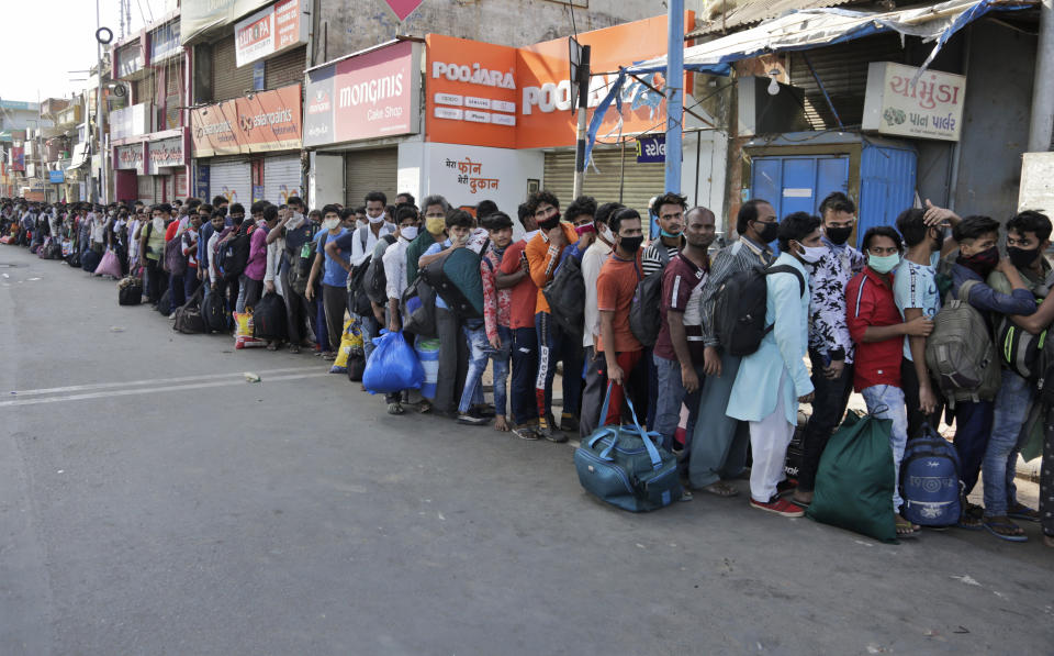 Migrant workers from other states trying to return to their homes stand in queue as they wait for transportation to a train station in Ahmedabad, India, Sunday, May 17, 2020. Tens of thousands of migrant laborers have been returning from big cities to their villages after losing jobs because of a countrywide lockdown imposed in late March to contain the spread of the coronavirus. (AP Photo/Ajit Solanki)