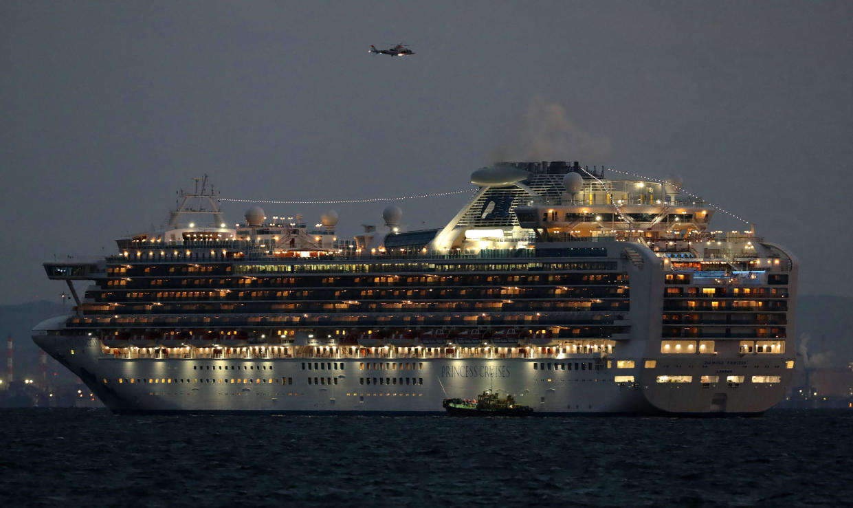 A small boat is pictured next to the Diamond Princess cruise ship with over 3,000 people as it sits anchored in quarantine off the port of Yokohama on February 4, 2020, a day after it arrived with passengers feeling ill. - Japan has quarantined the cruise ship carrying 3,711 people and was testing those onboard for the new coronavirus on February 4 after a passenger who departed in Hong Kong tested positive for the virus. (Photo by STR / JIJI PRESS / AFP) / Japan OUT (Photo by STR/JIJI PRESS/AFP via Getty Images)