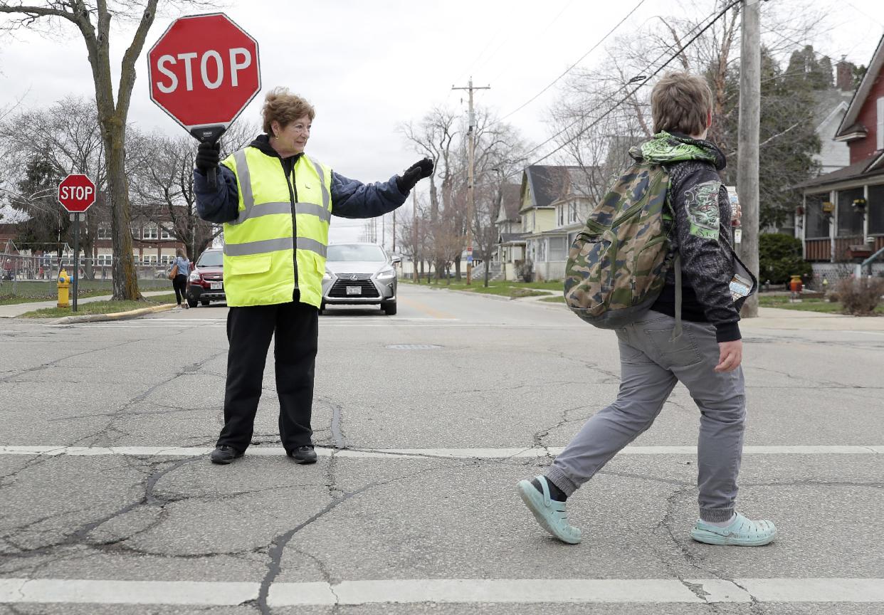 Crossing guard Judy La Count stops traffic as a student crosses the street in 2022 near Roosevelt Elementary School on Doty Island in Neenah. The school has since closed.