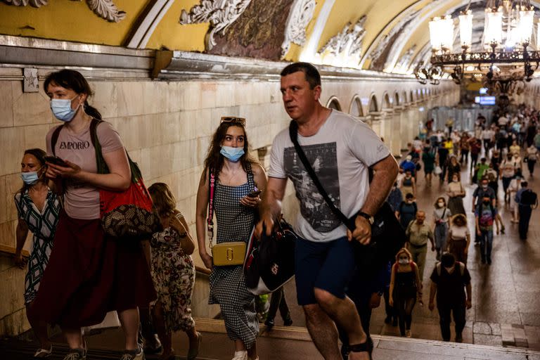 Las personas, algunos con mascarillas, caminan en una plataforma en el metro de Moscú