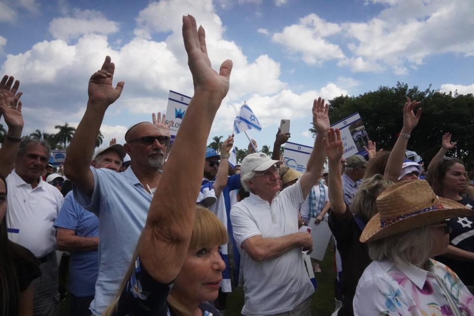 Demonstrators raise their arms Sunday afternoon in solidarity with Israel at a pro-Israel rally in downtown West Palm Beach.