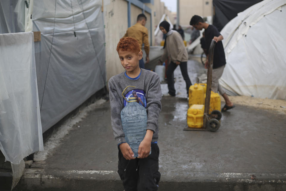 Displaced Palestinian carries water in a makeshift tent camp in Rafah, Gaza Strip, Thursday, Dec. 28, 2023. (AP Photo/Hatem Ali)