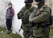 A boy looks at uniformed men, believed to be Russian servicemen, near a Ukrainian military base in the village of Perevalnoye, outside Simferopol, March 6, 2014. REUTERS/Vasily Fedosenko