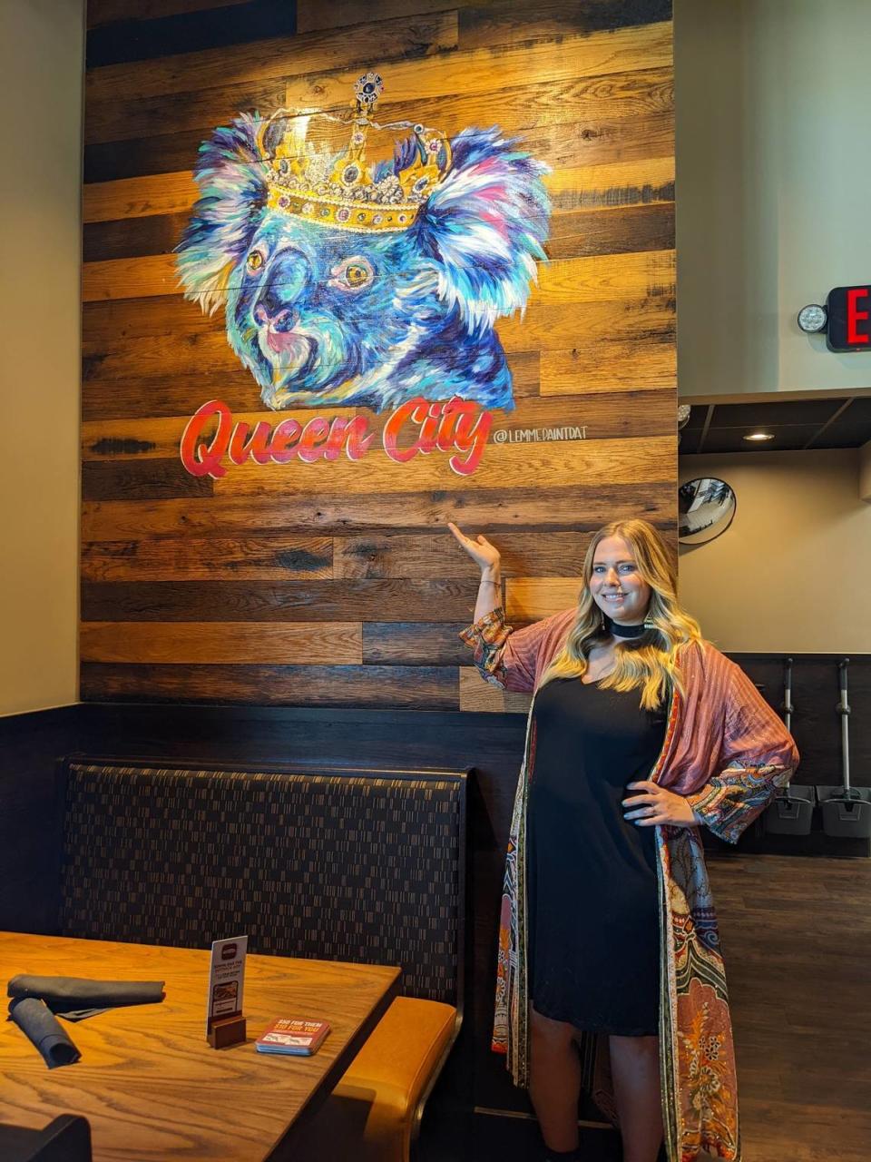Charlotte artist Lindsey Jenneman, owner of Lemmepaintdat, stands May 17 next to the painting she created for the recently opened Steele Creek Outback Steakhouse.