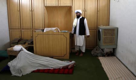 Hafiz Abdul Majid, administrator of the Al Haaj mosque, gestures to a lectern where Taliban chief Habibullah Akhundzada taught as another cleric sleeps on the ground in Kuchlak outside Quetta, Pakistan September 23, 2016. REUTERS/Naseer Ahmed