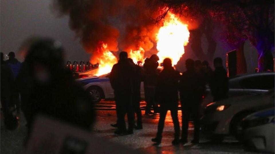 Un auto de policía en llamas durante una protesta.