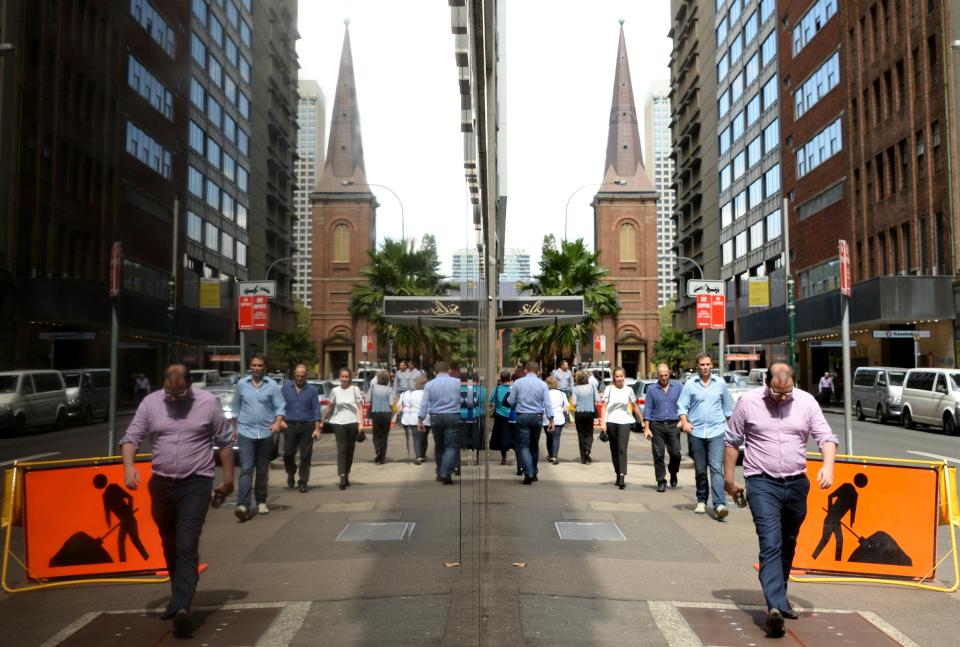 Office employees reflect on the Reserves Bank of Australia wall in the central business district of Sydney on April 2016. The Australian economy has slowed as the country exits an unprecedented mining investment boom that has helped it avoid a recession for 24 years, with the jobless rate hovering around a decade high and wage growth and business investment outside the resources sector both tepid. / AFP / SAEED KHAN        (Photo credit should read SAEED KHAN/AFP via Getty Images)