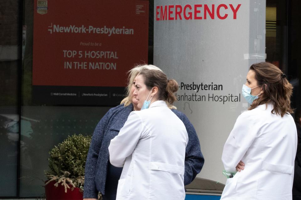 Medical personnel talk outside the emergency room at NewYork-Presbyterian Lower Manhattan Hospital, Wednesday, March 18, 2020, in New York.