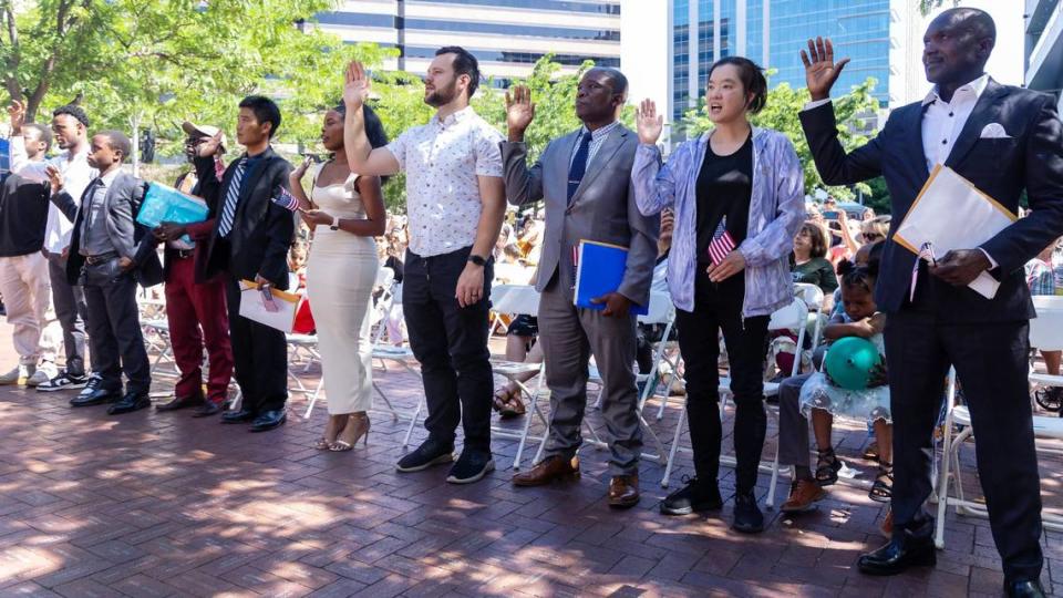 Ten people took their oaths of citizenship to become Americans at World Refugee Day at Grove Plaza in downtown Boise on Saturday. Uchama, in a red suit, and Keju, in a gray suit, can be seen at left.