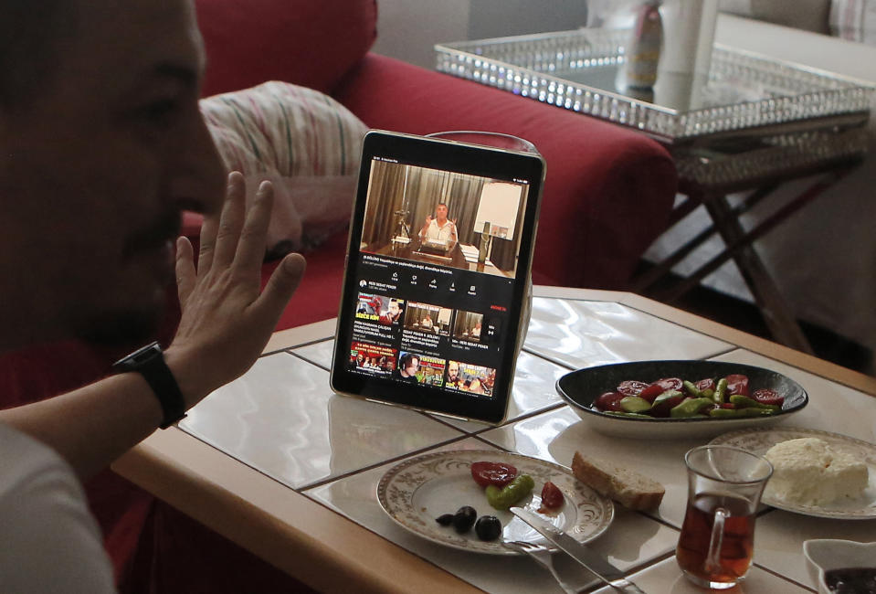 Alparslan Atas, 41, left, gestures as he talks to his wife Gulistan, 38, over breakfast at their home in Istanbul, while watching on a tablet Sedat Peker, a Turkish fugitive crime boss on a video, Sunday, June 6, 2021. Sunday is the day the 49-year-old convicted crime ringleader posts the latest installation of his hour-long tell-all videos from his stated base in Dubai that have captivated Turkey and turned the mobster into an unlikely social media phenomenon. The convicted crime ringleader has been dishing the dirt on members of Turkish President Recep Tayyip Erdogan’s ruling party. The allegations range from drug trafficking and a murder cover-up to weapons transfers to Islamic militants. (AP Photo/Mehmet Guzel)