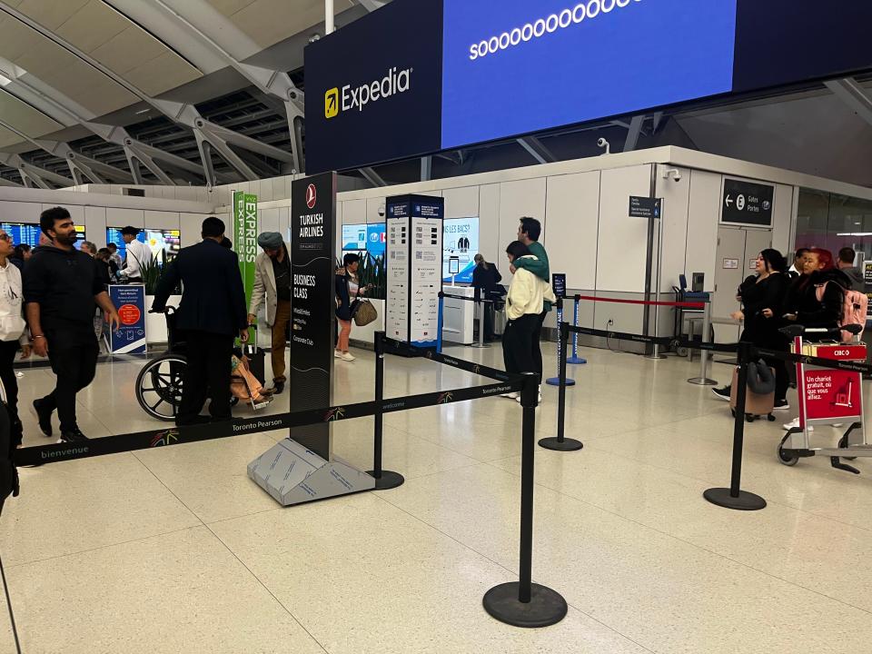 Line at airport with people rushing back and forth and rope separating people in line