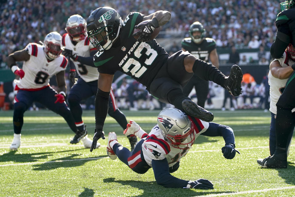 New York Jets running back James Robinson (23) is upended by New England Patriots cornerback Jack Jones (13) during the third quarter of an NFL football game, Sunday, Oct. 30, 2022, in New York. (AP Photo/John Minchillo)