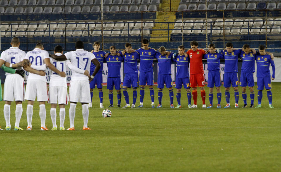 Players of Ukraine, right, and U.S. hold a minute’s silence in honor of victims of recent violent clashes in the Ukrainian capital before the start of their international friendly match at Antonis Papadopoulos stadium in southern city of Larnaca, Cyprus, Wednesday, March 5, 2014. The Ukrainians are facing the United States in a friendly on Wednesday in Cyprus, a match moved from Kharkiv to Larnaca for security reasons. (AP Photo/Petros Karadjias)