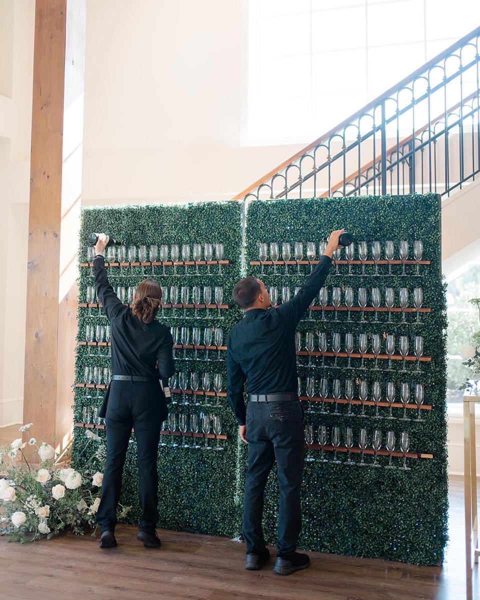 Waitstaff fills up a champagne wall.