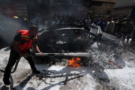 A member of Palestinian Civil Defence extinguishes a fire in the car of a Hamas commander who was killed in an Israeli air strike, in Gaza City May 5, 2019. REUTERS/Ashraf Abu Amrah