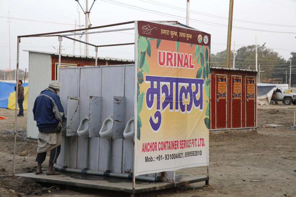 In this Monday, Jan. 14, 2019, photo, a devotee uses newly put up portable toilet at the tent city for the spiritual-cleansing Kumbh Festival in Prayagraj, India. The skies over the confluence of sacred rivers in north India where millions of Hindu priests and pilgrims have come to wash away their sins for the Kumbh Mela, or pitcher festival, that begins this week are thick with toxic dust, a sign that Indian government officials are struggling to grapple with India's worsening air pollution. (AP Photo/Rajesh Kumar Singh)