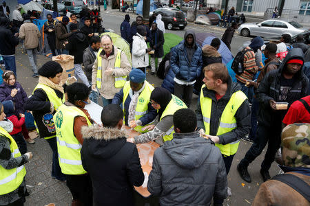 Migrants queue for a free meal distributed by the Adventist Development and Relief Agency International (ADRA) humanitarian agency in Paris. REUTERS/Charles Platiau