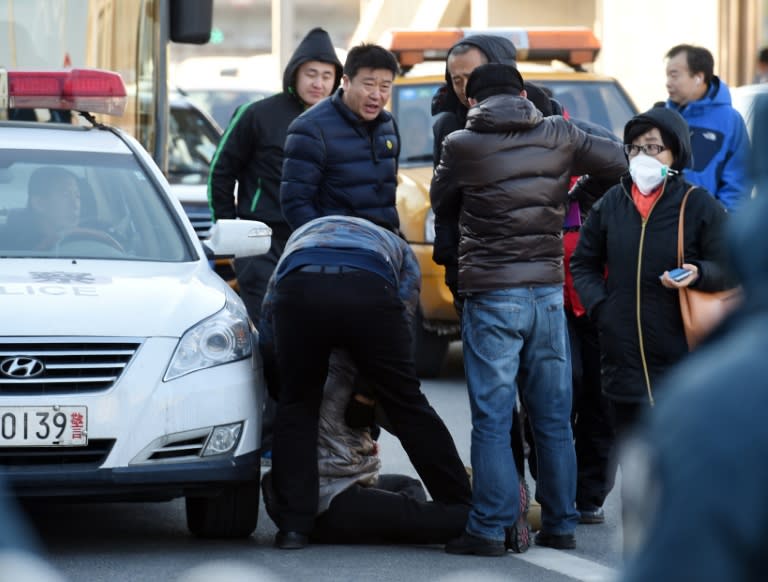 A man (C) attempts to lead away a supporter of jailed Chinese journalist Gao Yu, outside the Beijing City High Court, on November 26, 2015