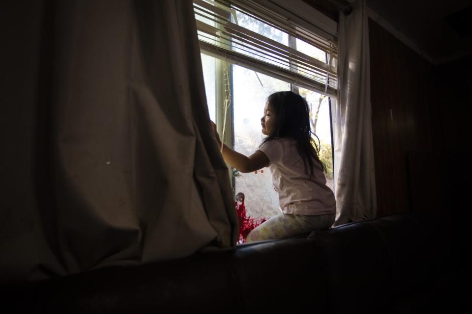 A young girl sits looking out a window